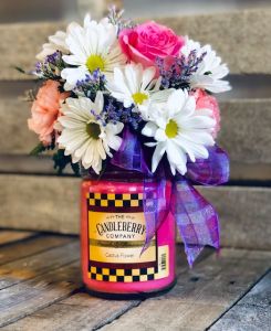 Candleberry jar candle with a bouquet on top.
